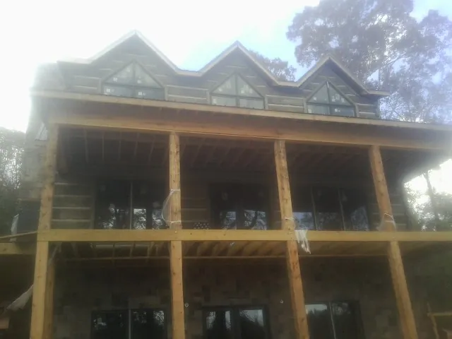 Dormers and porch framing on a large log home under construction — Roof Coating work by our crew in Homerville