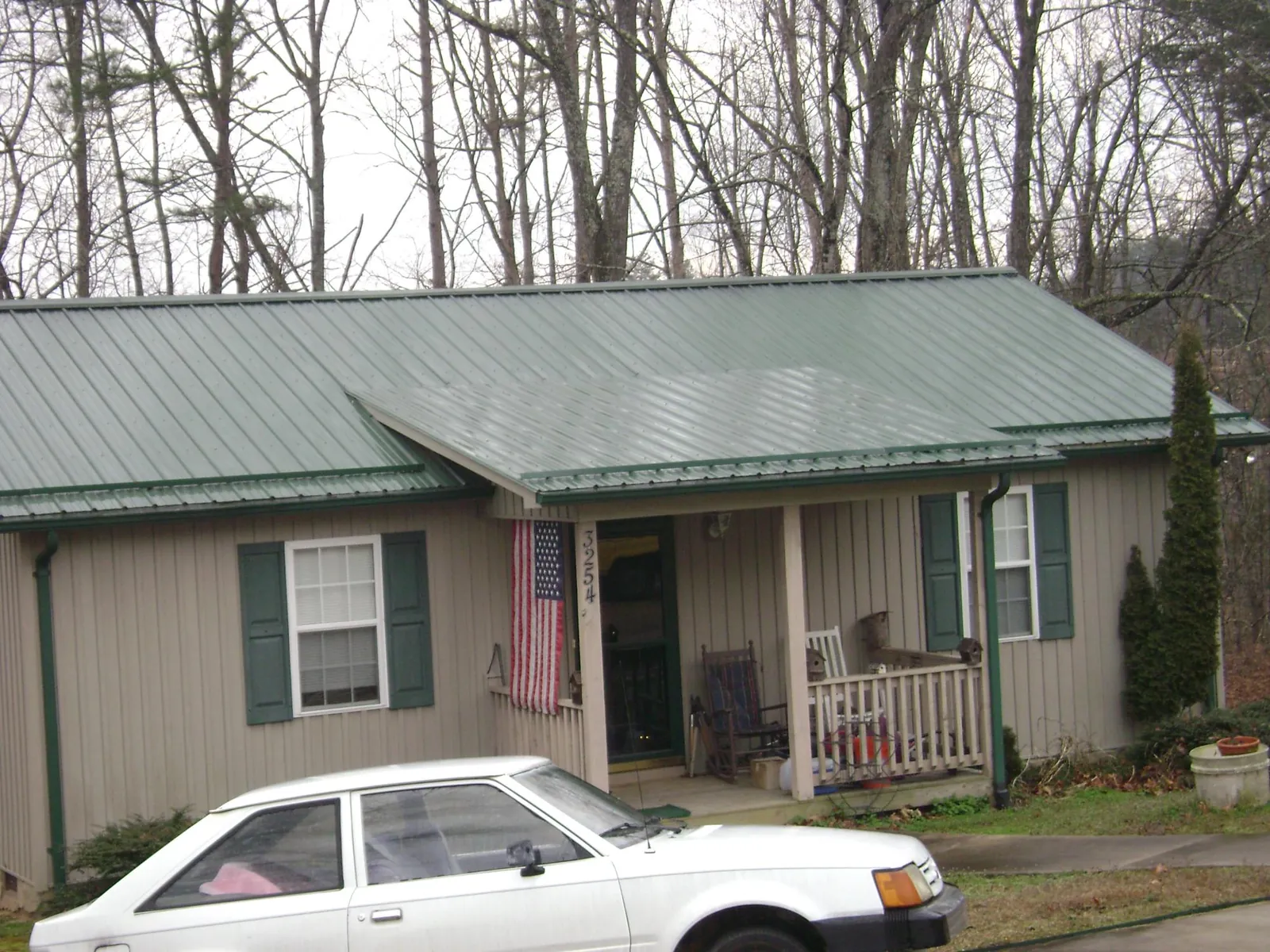 Green metal roof and front porch on a tan sided cottage in Homerville